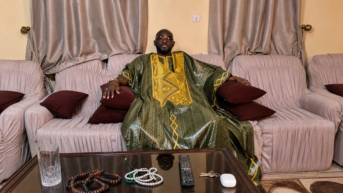 Marabout Djibril in a green and gold boubou, prayer beads laid out in front of him