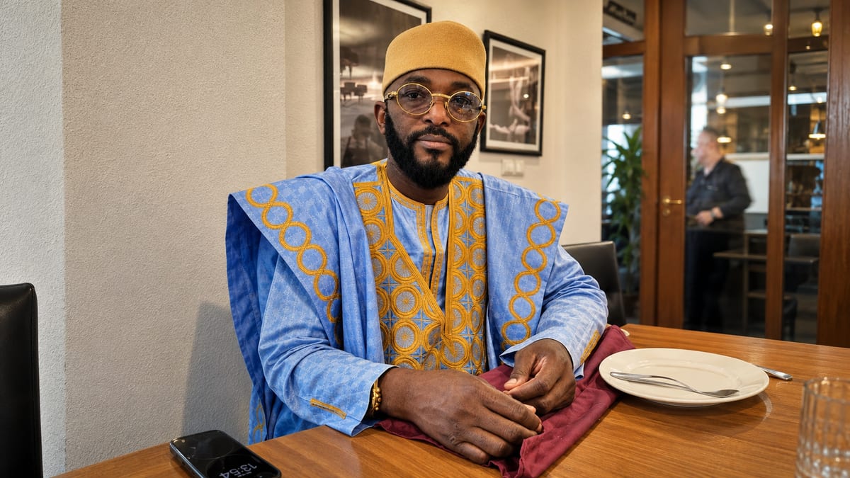 Marabout Djibril in a blue and gold boubou, seated at a consultation table